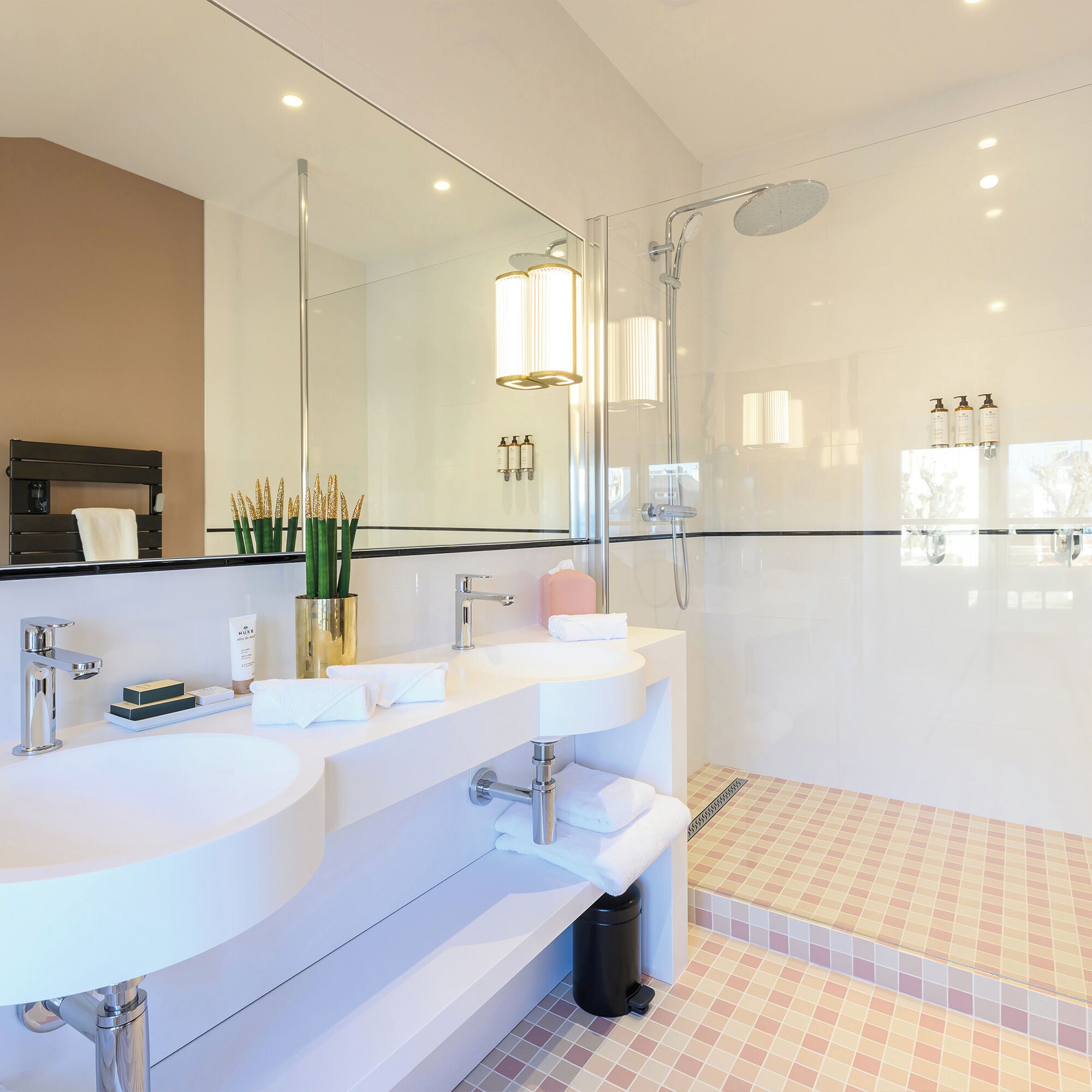 Une salle de bain moderne avec deux lavabos, un grand miroir et une douche.