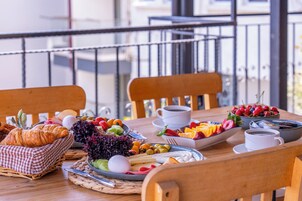 A breakfast table with croissants, fruits, cheese, and coffee cups.