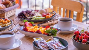 Ein Esstisch mit verschiedenen Früchten, Gebäck und einer Tasse Kaffee.