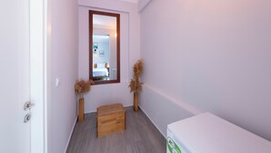 Ein schmaler Flur mit einer hölzernen Bank, einem weißen Schrank und zwei hohen Vasen mit Trockenpflanzen.