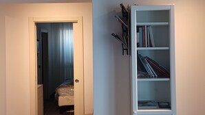 Une pièce comprenant un lit, une bibliothèque et une porte donnant sur une autre pièce.