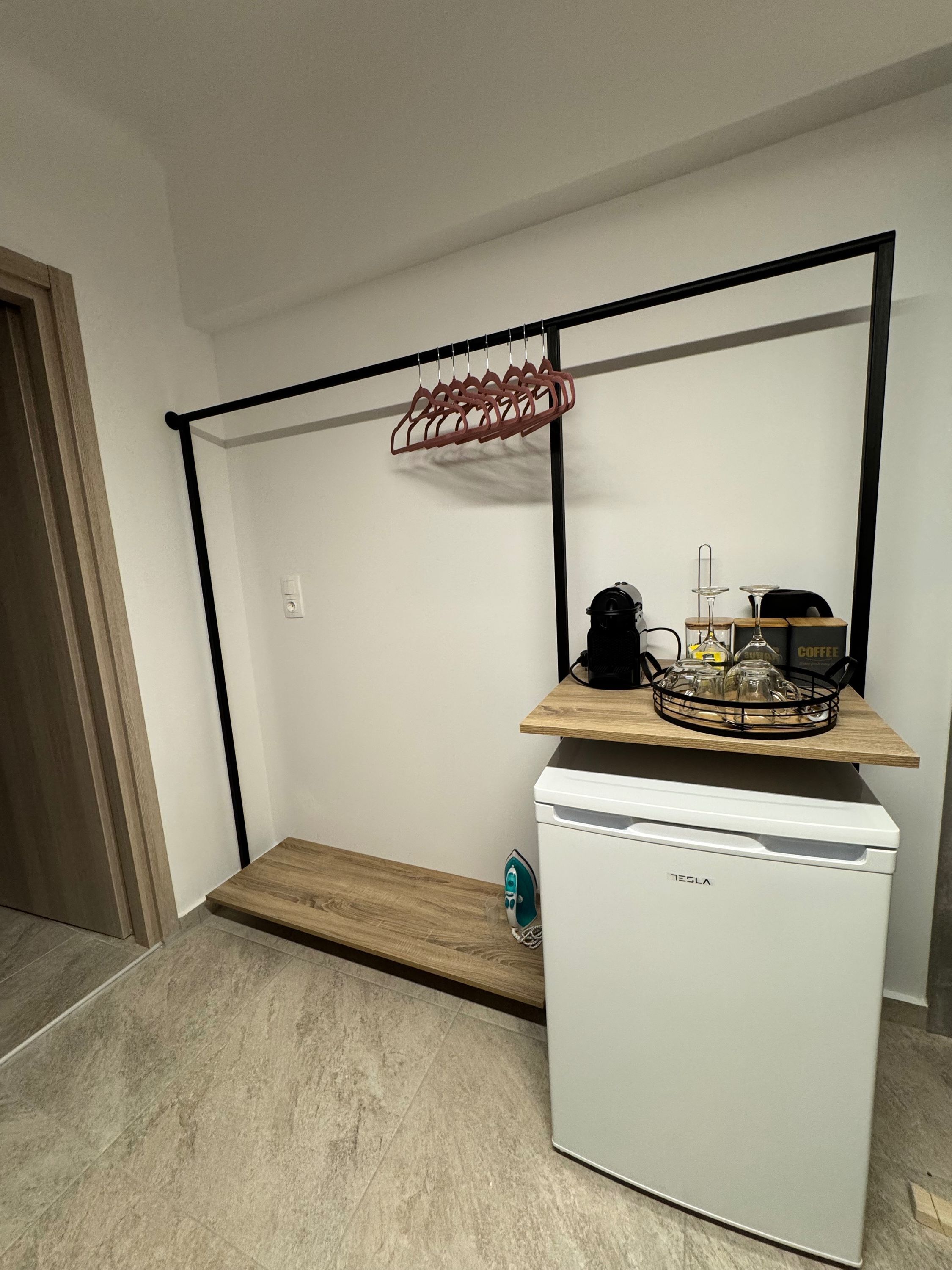 A compact kitchen with a white refrigerator, a wooden countertop, and a hanging clothes rack.