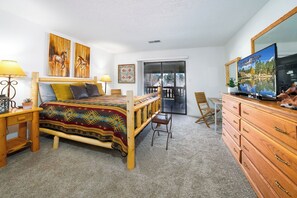 A bedroom with a bed, a TV, a desk, and a chair.