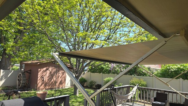 A covered outdoor deck with a hammock, wicker furniture, and a grill. - Spacious home in the heart of Emmett (Emmett)