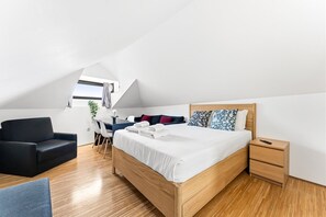 Quarto moderno com cama de madeira, uma escrivaninha, uma cadeira e uma mesa de cabeceira.