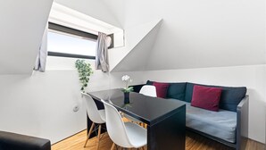 A modern loft bedroom with a dining area, a sofa, and a small table.