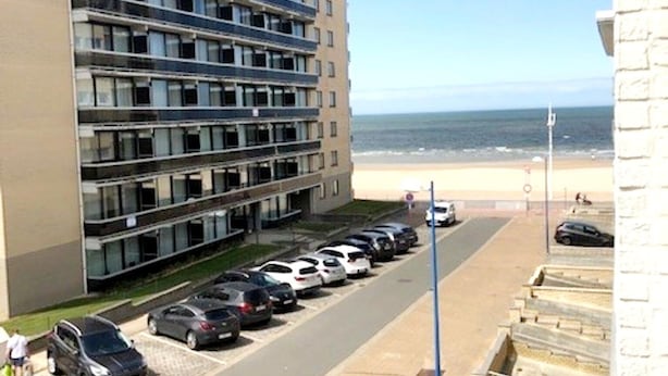 A multi-story hotel with a parking lot in front, a beach view, and a clear sky. - Well-kept Corner Apartment in Koksijde (Koksijde)