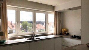 A modern kitchen with a large window, a sink, and cabinets. - Well-kept Corner Apartment in Koksijde (Koksijde)