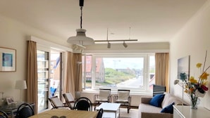 A modern hotel room with a dining area, a sofa, and a view of the city. - Well-kept Corner Apartment in Koksijde (Koksijde)
