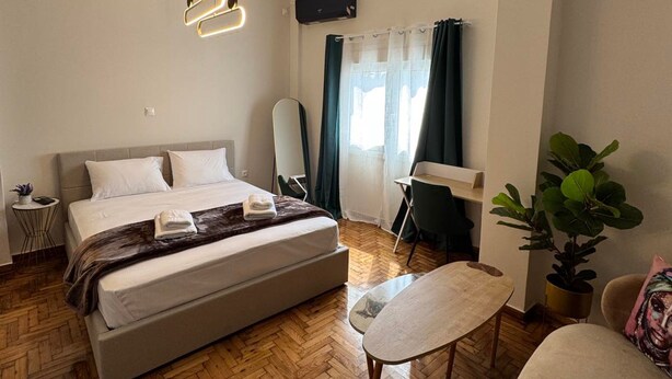 A modern bedroom with a large bed, a desk, a chair, and a potted plant. - Athenian Stay Chara s 2 Apartment (Chalandri)