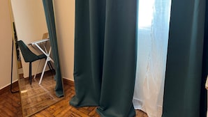 A room with a wooden floor, a green chair, a mirror, and a window with a sheer curtain. - Athenian Stay Chara s 2 Apartment (Chalandri)