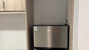 A stainless steel refrigerator in a kitchen with wooden cabinets and a green chair. - Athenian Stay Chara s 2 Apartment (Chalandri)