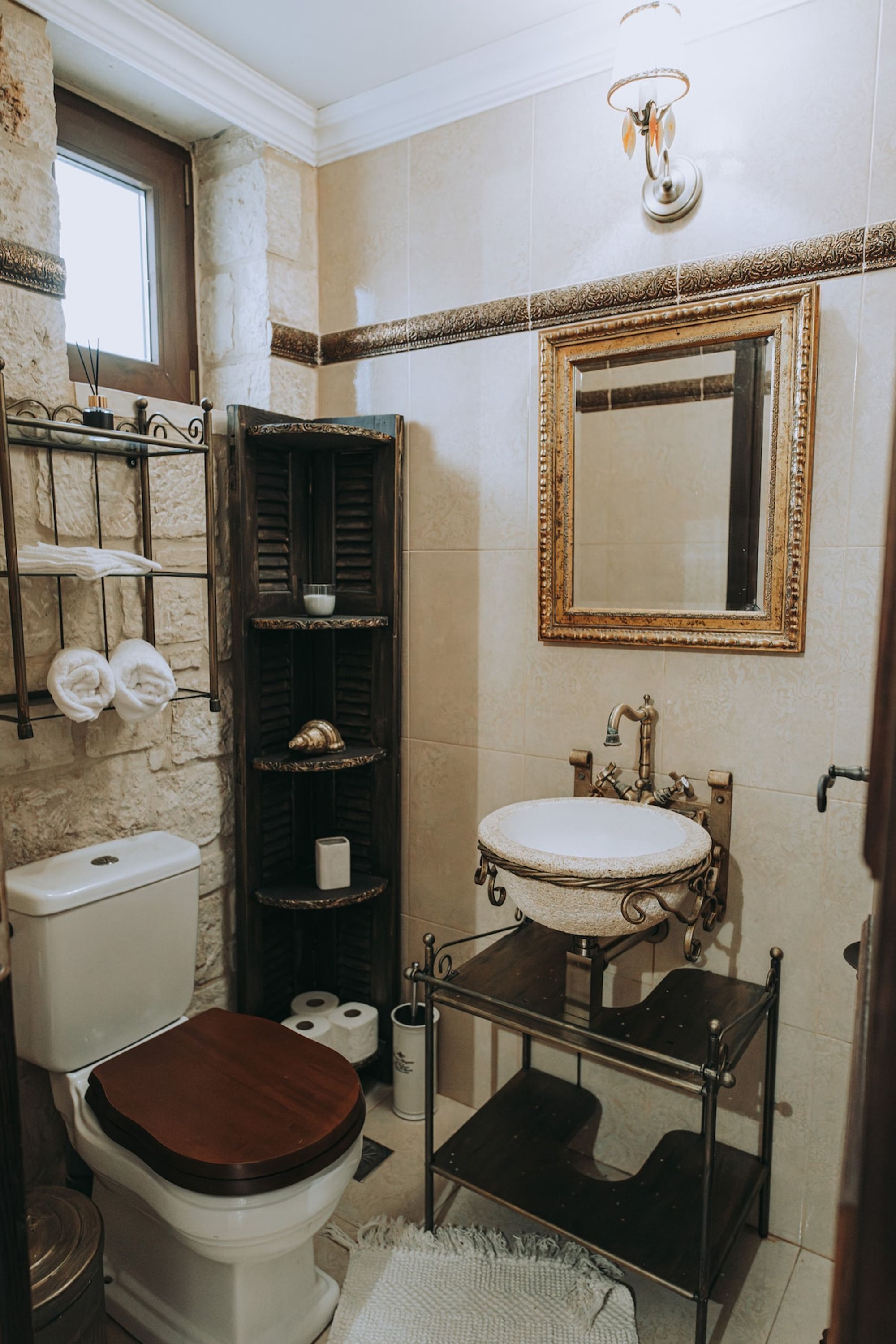 Ein Badezimmer mit Toilette, Waschbecken, Spiegel, Handtuchhalter und Regalen.