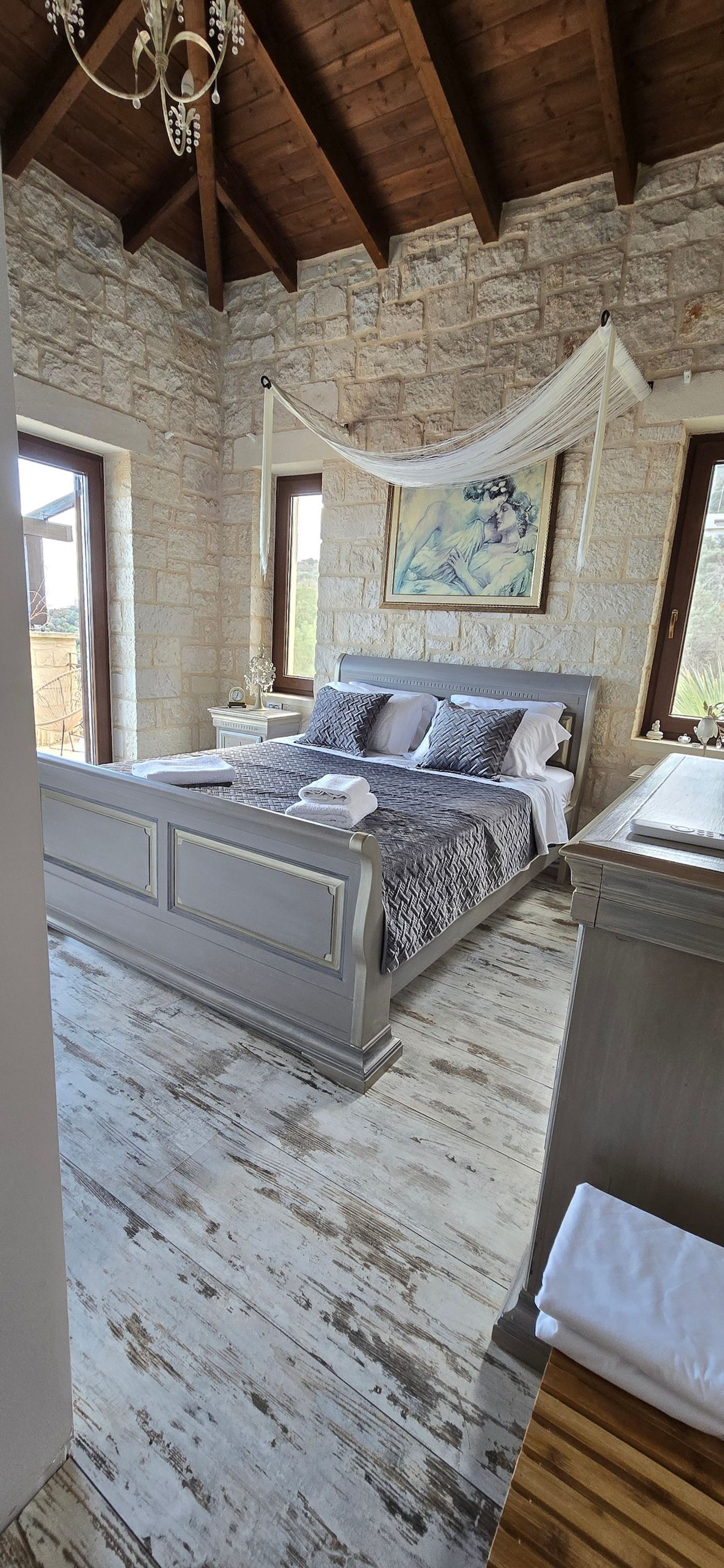 Ein Schlafzimmer mit Steinwand, einem Himmelbett und Blick ins Freie.