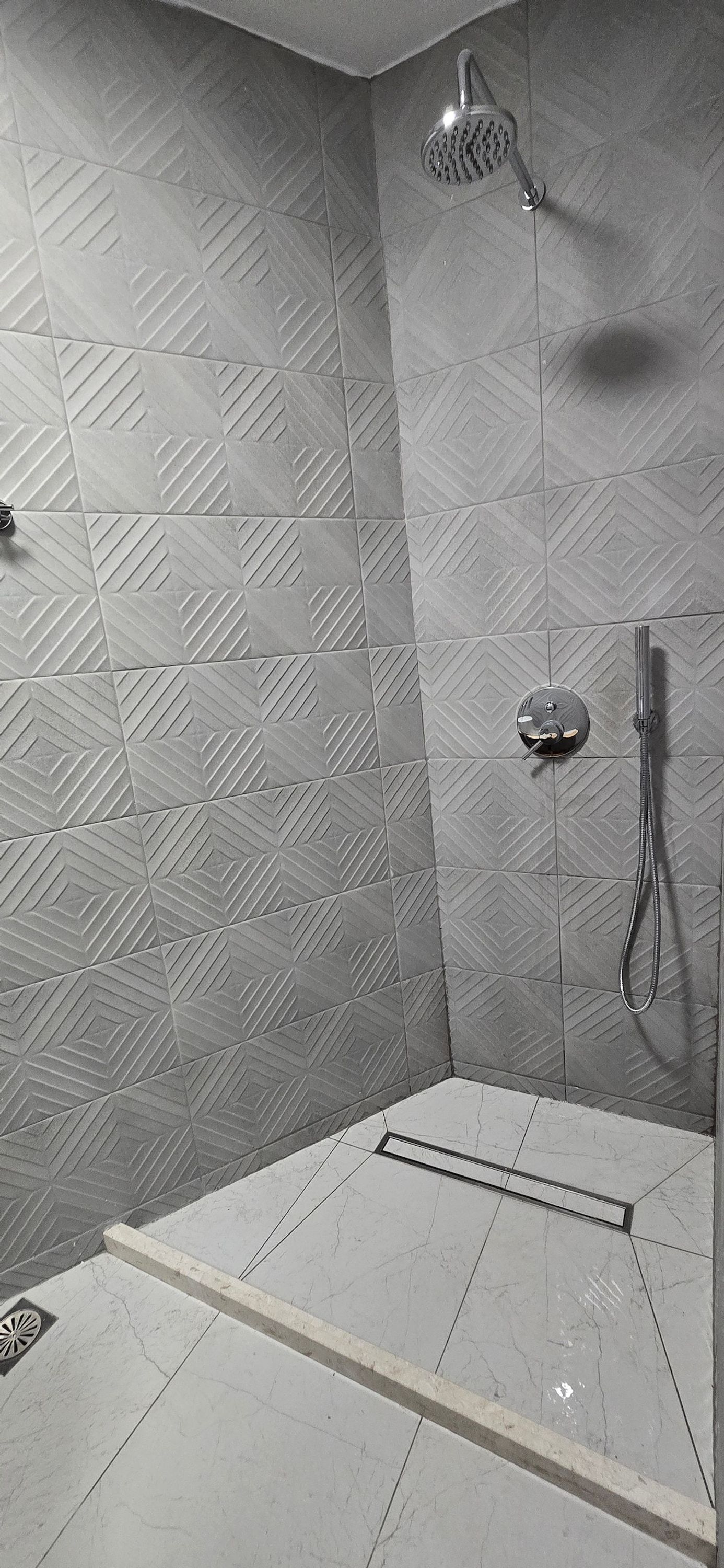 A shower area with a geometric tile pattern on the walls and floor.