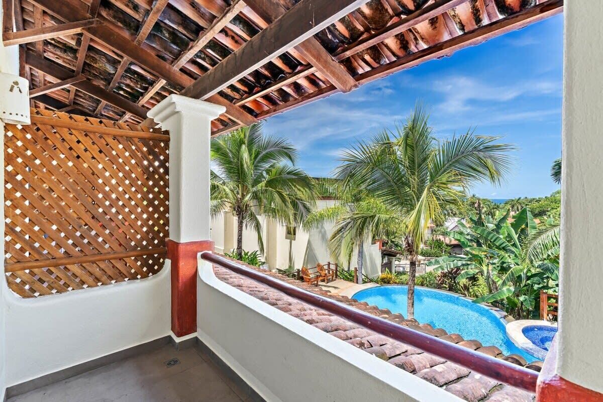 A balcony with a view of a swimming pool and palm trees.