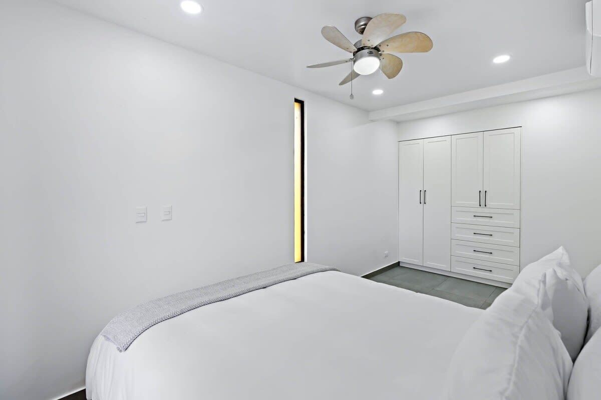 A bedroom with a bed, a wardrobe, and a ceiling fan.