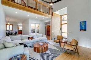 Un salón amplio con techo alto, una escalera de madera y un comedor con vistas a la cocina.