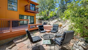 A wooden deck with outdoor furniture, a fire pit, and a stone wall.