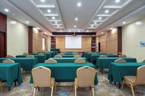 A conference room with rows of tables and chairs, a projector screen, and a carpeted floor. - Weihai Electronic Hotel (Weihai)
