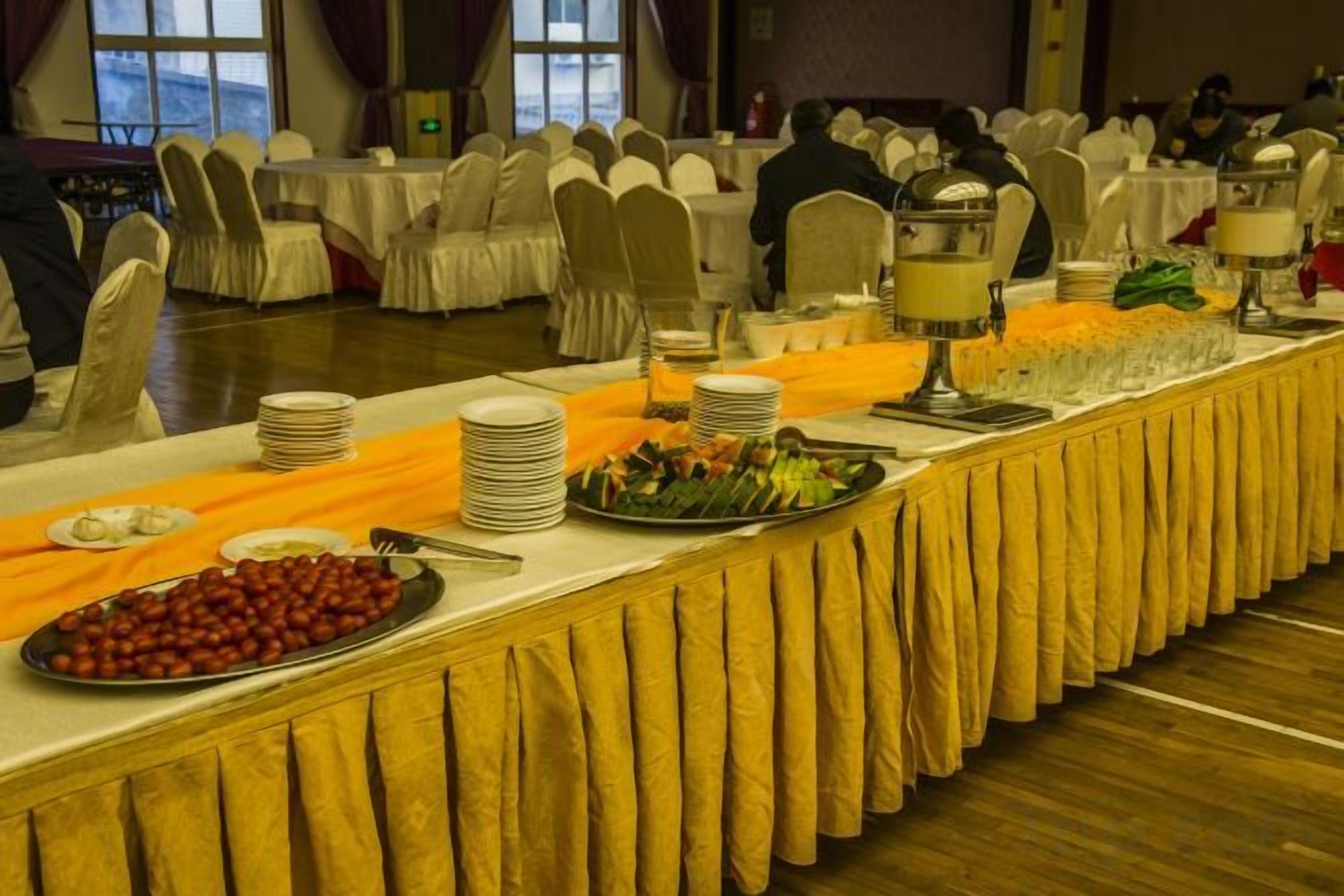 A buffet setup with multiple serving stations, white tablecloths, and a variety of food items.