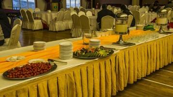 A buffet setup with multiple serving stations, white tablecloths, and a variety of food items.
