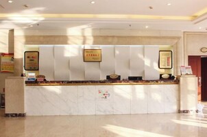 Una mesa de recepción de hotel con encimera de mármol, certificados enmarcados y una zona de espera.