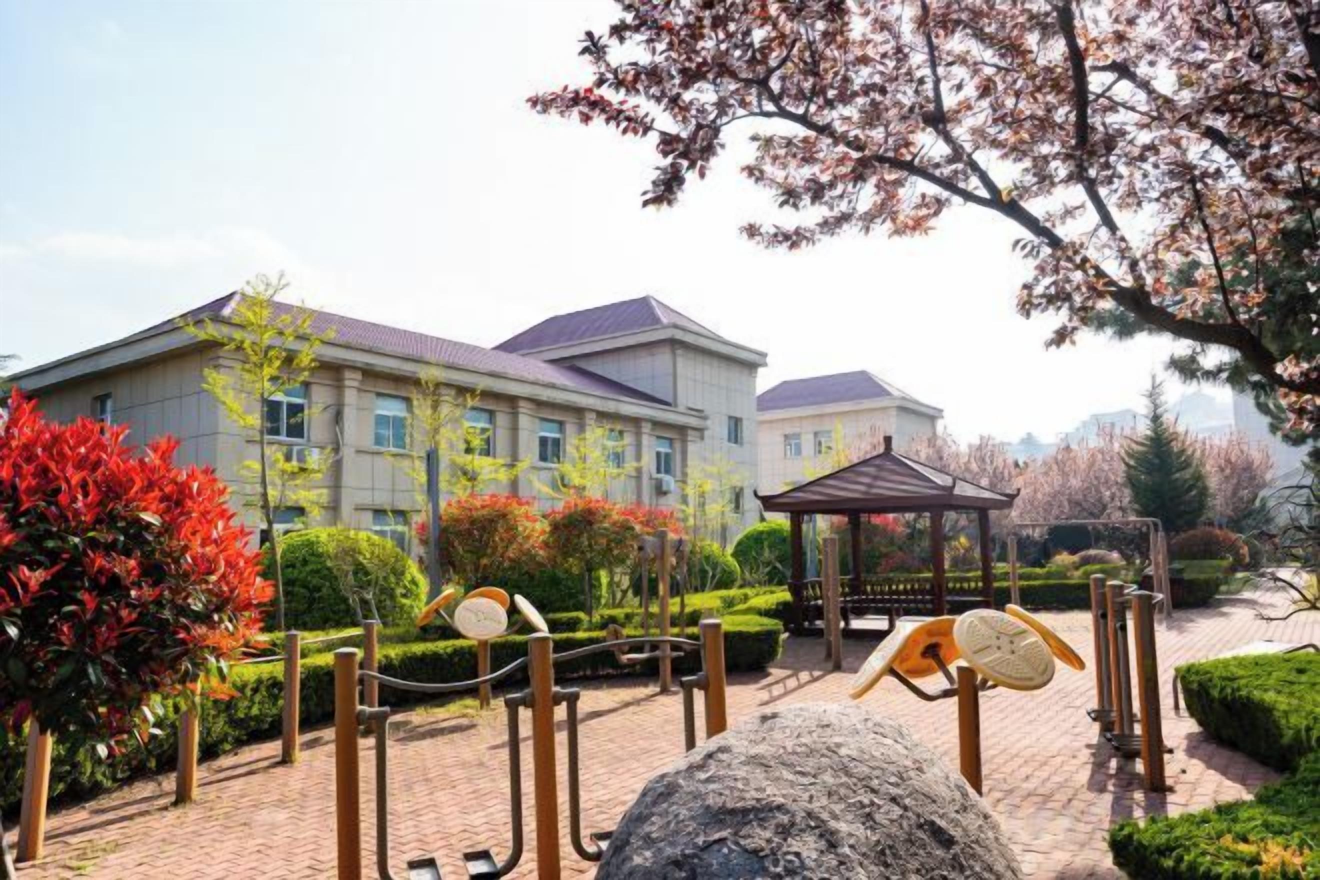 A building with a paved courtyard, a gazebo, and a large rock.