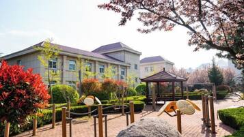 A building with a paved courtyard, a gazebo, and a large rock.