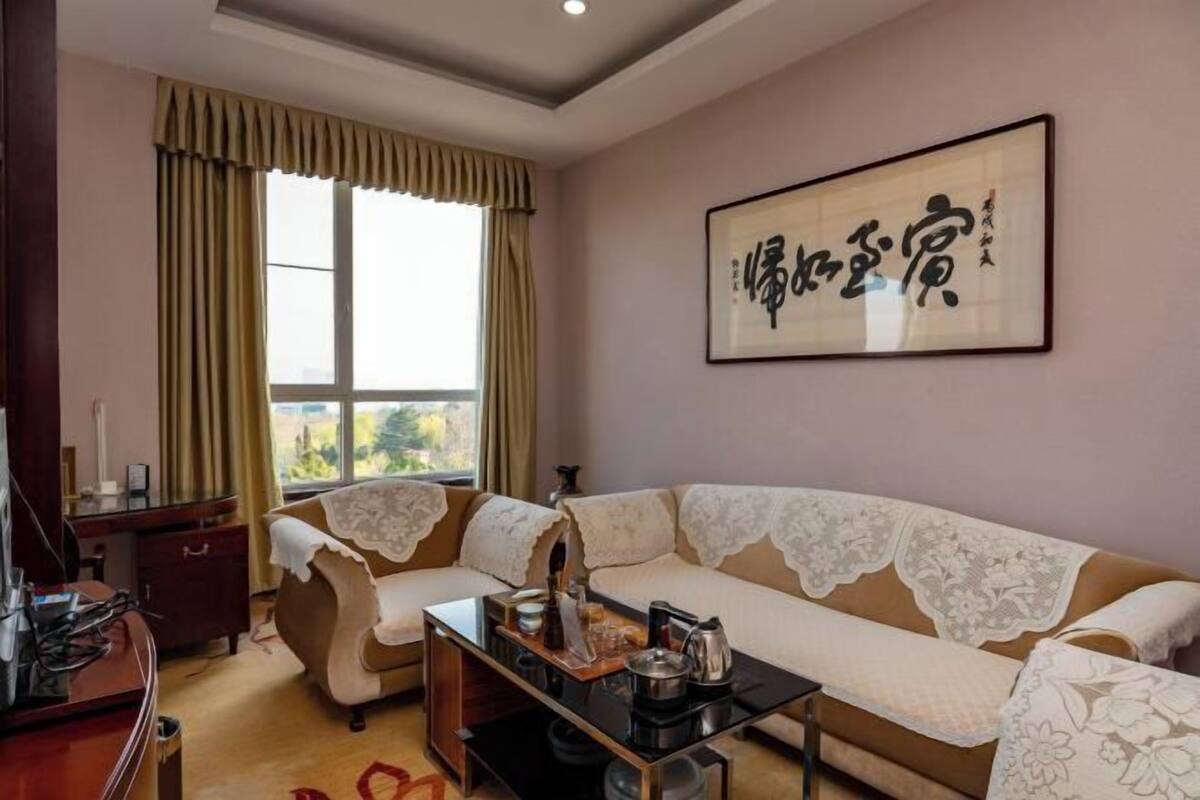 A living room with a sofa, a coffee table, and a window with curtains.