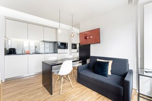 Eine moderne Küche mit Essbereich, einer Couch und einem Fernseher.