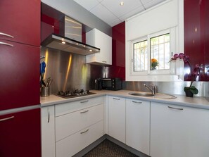 A modern kitchen with stainless steel appliances, white cabinets, and a window with a view of the outdoors. - Apartment in Roses With Sea Views & Pool (Roses)