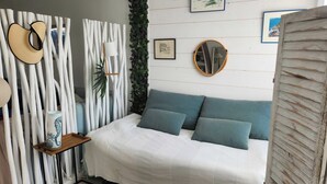 A bedroom with a bed, a bedside table, a mirror, and wall-mounted pictures.