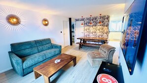 A modern living room with a sofa, coffee table, and a TV. - Charming flat in the heart of Gérardmer (Gérardmer)