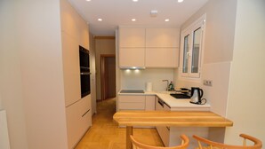 A compact kitchen with a wooden table and chairs, a built-in oven, and a window above the sink. - Athens top floor stylish 2 min walk to metro Panepistimio (Athina)