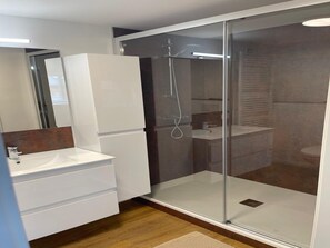 A modern bathroom with a glass-enclosed shower, a white sink, and a wooden vanity.