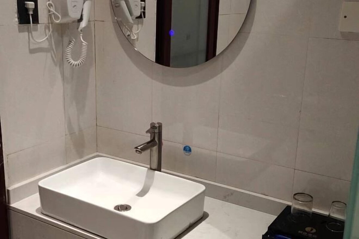 A modern bathroom with a white sink, a mirror, and a towel rack.