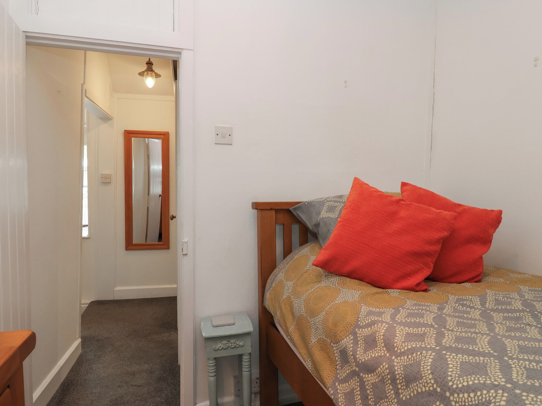 Ein Schlafzimmer mit einem Bett, einem Nachttisch, einem kleinen Tisch und einem Spiegel.