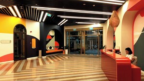 A modern lobby with a reception desk, a glass entrance, and a patterned floor.