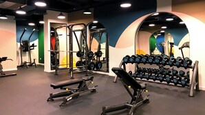 A gym with various exercise equipment, including dumbbells, benches, and weight machines.