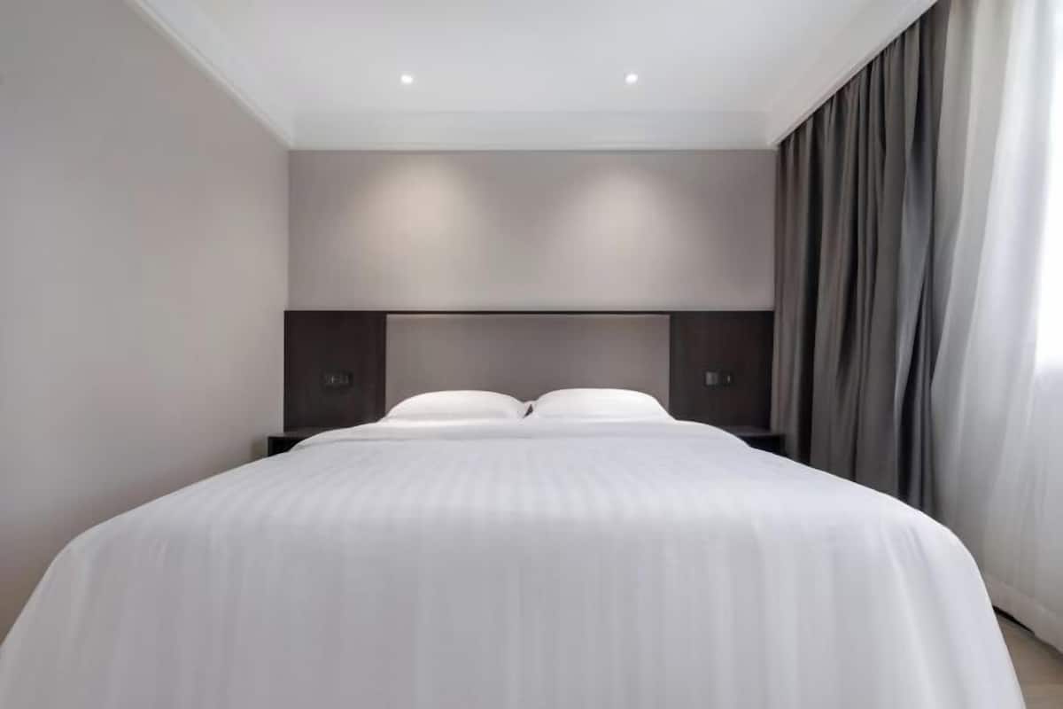 Ein modernes Hotelzimmer mit einem großen Bett, einer Kopfteilbeleuchtung und Blick auf die Stadt.