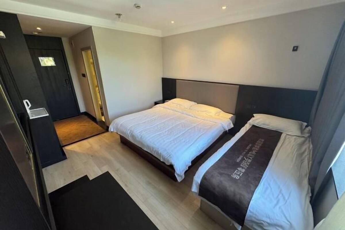 Ein modernes Hotelzimmer mit zwei Betten, Holzboden und einem dunkelbraunen Kopfteil.