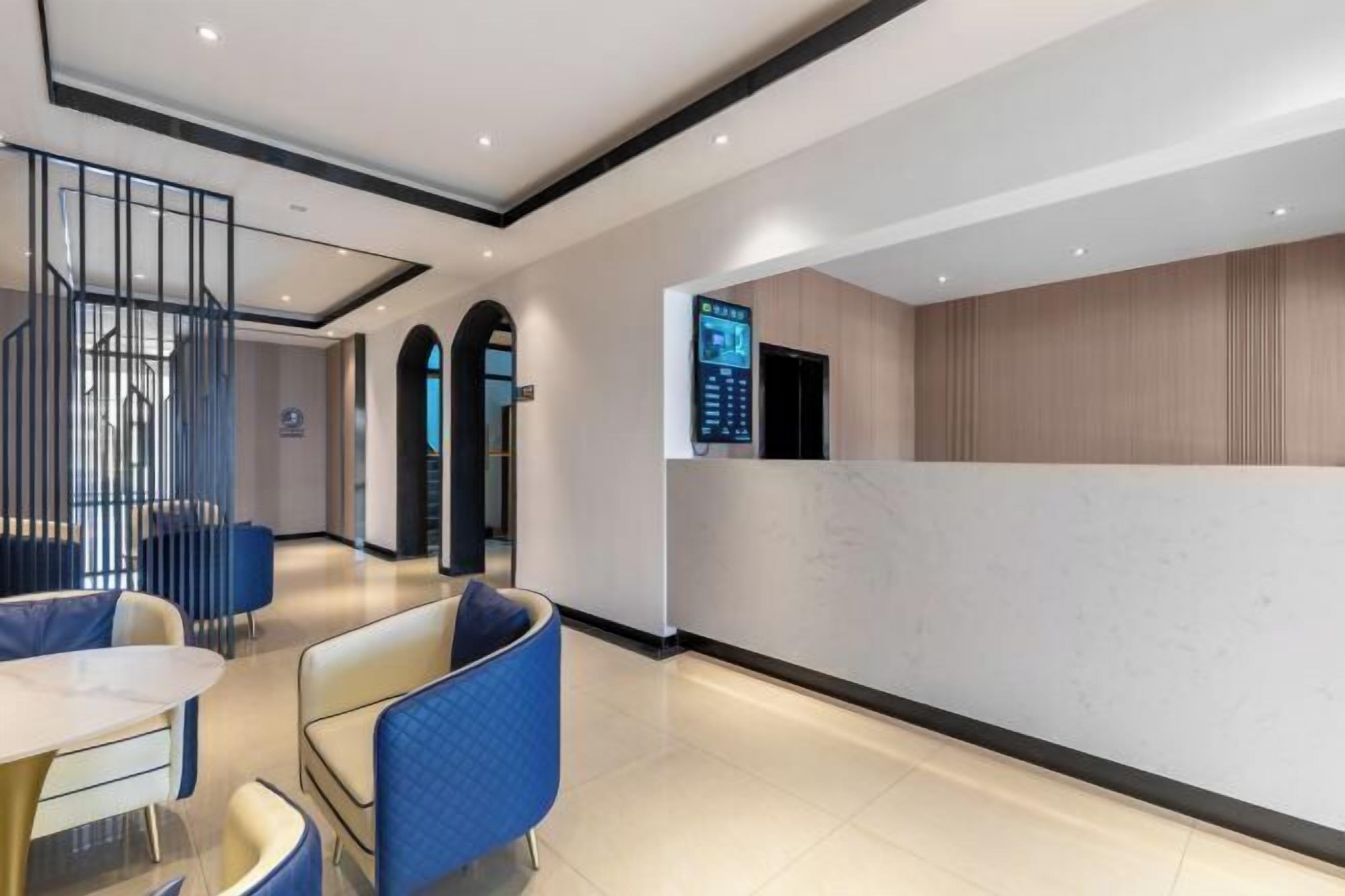 Um hall de hotel moderno com balcão de recepção, área de estar e escadaria.