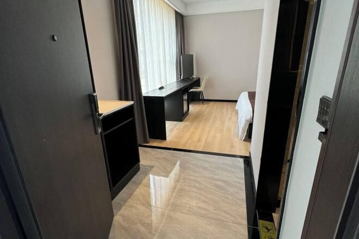 A hotel room with a desk, chair, and a television.