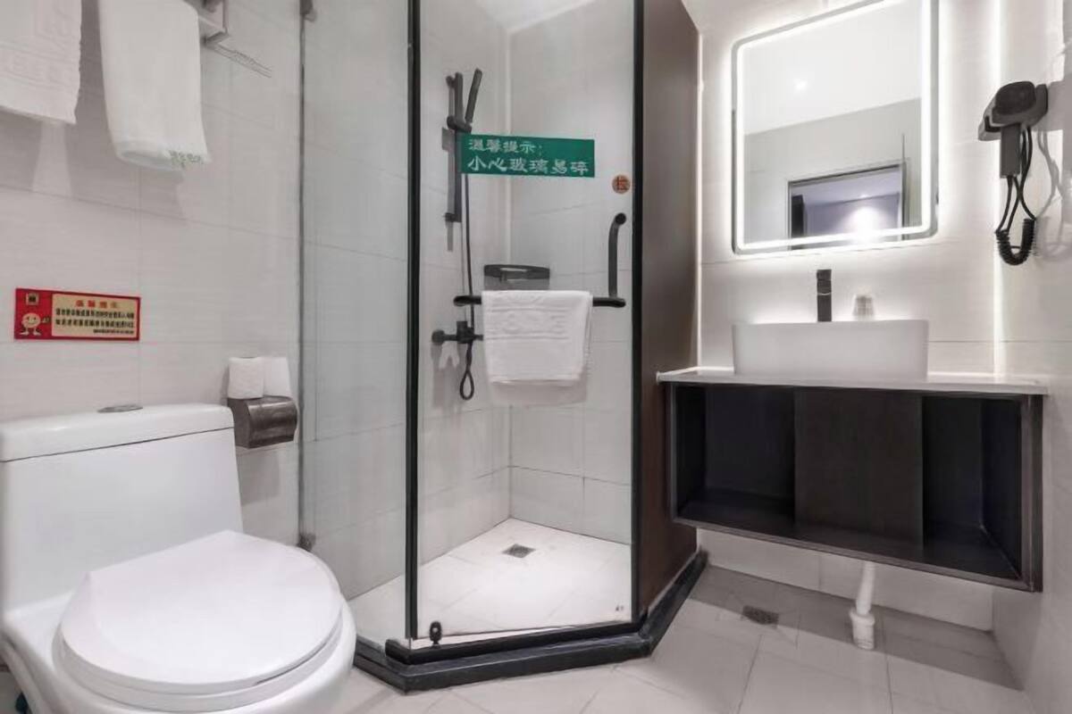Ein modernes Badezimmer mit einer Glasdusche, einer weißen Toilette, einem Waschbecken mit Spiegel und einem Handtuchhalter.