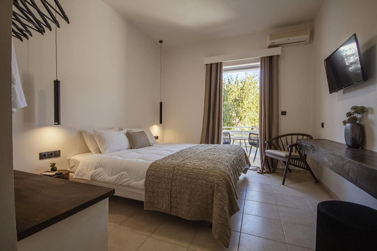 A bedroom with a bed, bedside table, and a TV mounted on the wall.