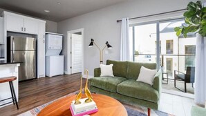 Eine moderne Wohnung mit Küche, einem grünen Sofa und einem großen Fenster.