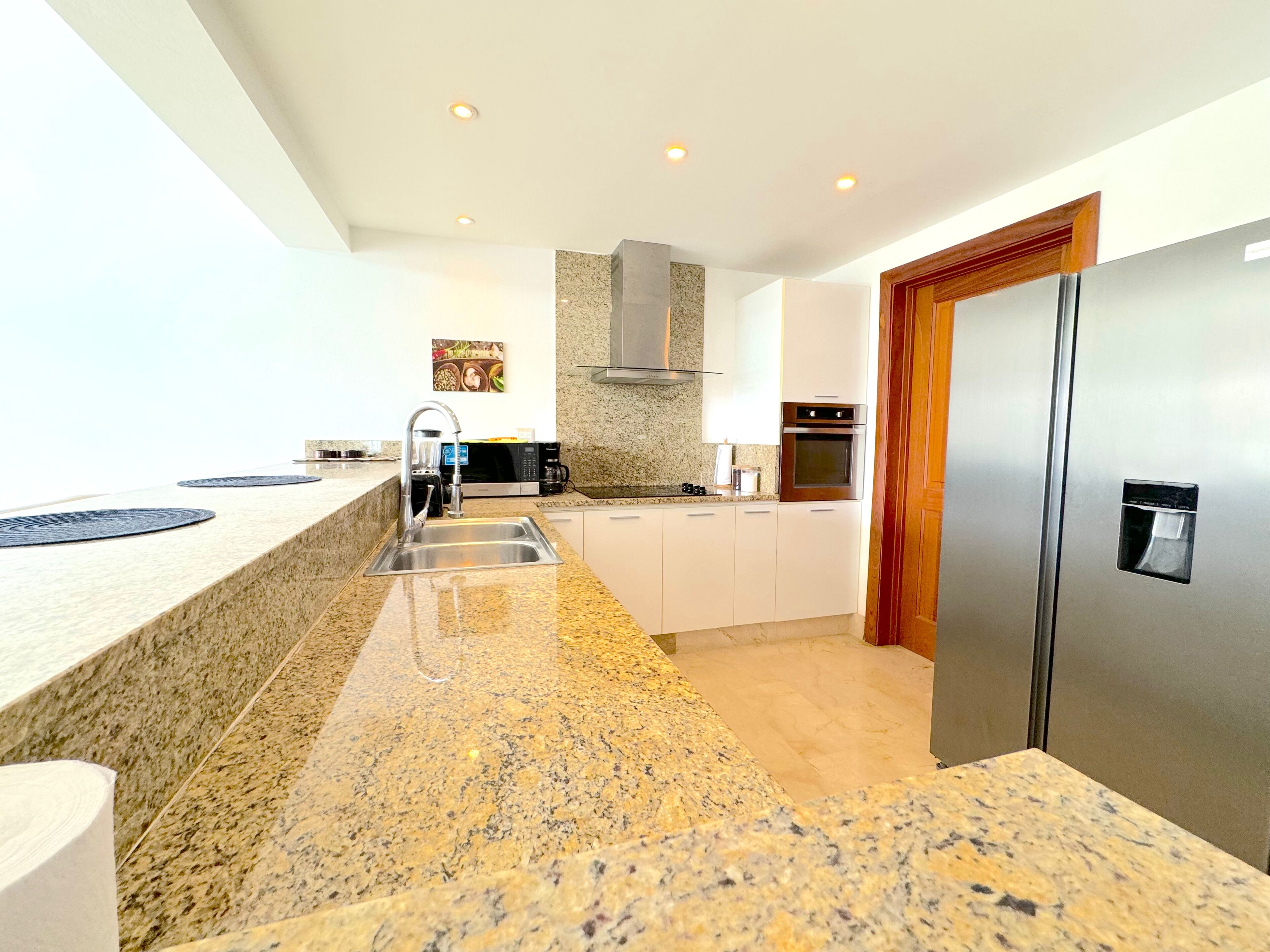 A modern kitchen with granite countertops, stainless steel appliances, and white cabinetry.