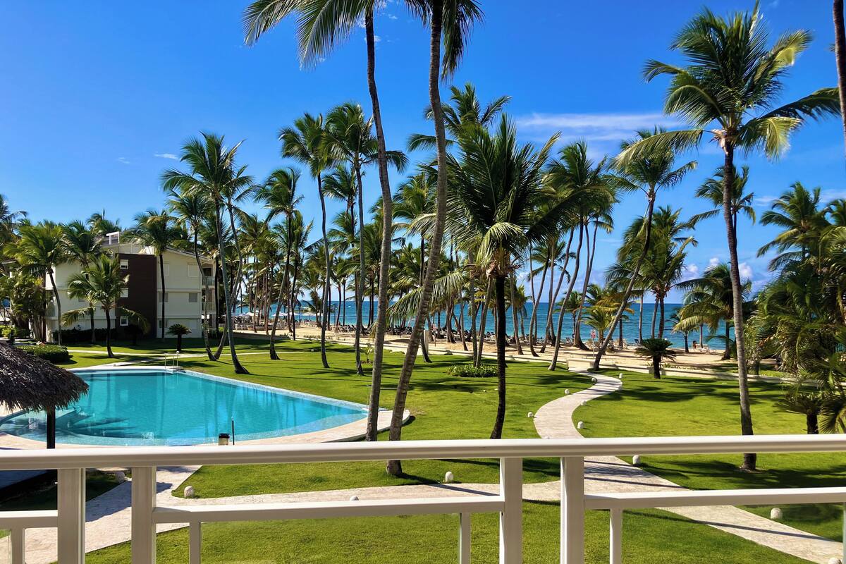 Ein Pool, umgeben von Palmen, mit Blick auf den Strand.
