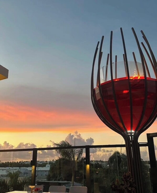 A sunset view from a balcony with a decorative glass structure.